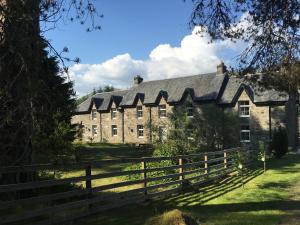 an old stone house with a fence in front of it at Ewich House B&B in Crianlarich