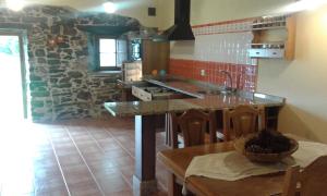 a kitchen with a table and a stone wall at La casa de atrás in Arancedo