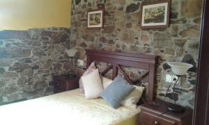 a bedroom with a stone wall with a bed and two lamps at La casa de atrás in Arancedo