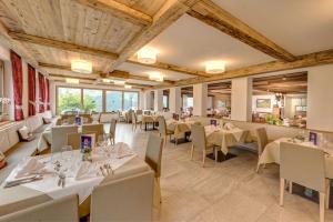 a restaurant with white tables and chairs and windows at Hotel Alpenland in Moso