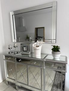 a silver dresser with a mirror on a wall at LUX Apartament in Suwałki
