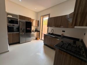 a large kitchen with wooden cabinets and stainless steel appliances at Villa del Sur 5 min du centre in Marrakech