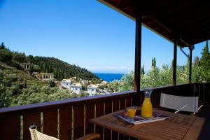 a wooden table with two glasses of orange juice on a balcony at Evridiki's Villas in Agios Nikitas