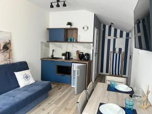 a living room with a blue couch and a kitchen at Blue Apartment B Dębina - prywatny taras na dachu , 400 m od morza, in Debina