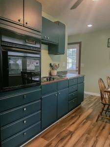 a kitchen with blue cabinets and a table and chairs at Blue Cottage with Game Room Deck & Hot Tub in Logan