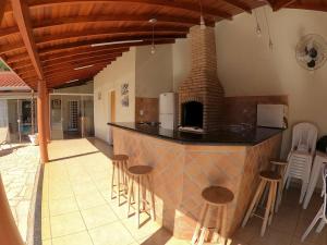 a kitchen with a bar with stools and a fireplace at Casa com área de lazer completa in Ribeirão Preto