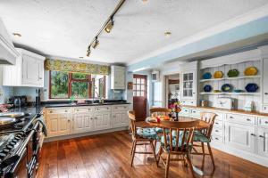 a kitchen with white cabinets and a table with chairs at Churchill Country Retreat By My Getaways in Lewes