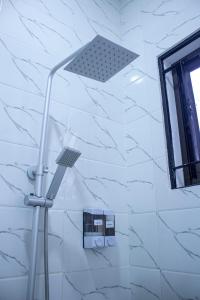 a shower light in a bathroom with white tiles at Spacious 2 bedroom home with equipped kitchen in Dar es Salaam