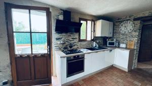 a kitchen with white cabinets and a clock on the wall at Gîte La Loge in Corné