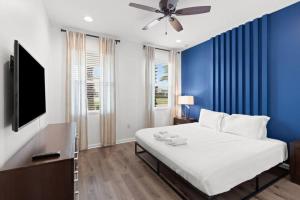 - une chambre avec des murs bleus et un lit avec un ventilateur de plafond dans l'établissement Ultimate 8br Family Getaway, à Kissimmee