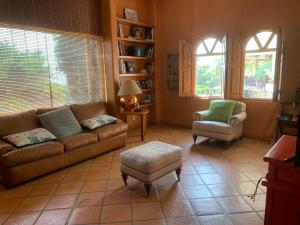 a living room with a couch and a chair and two windows at Casa Vinca in San Juan Cosalá