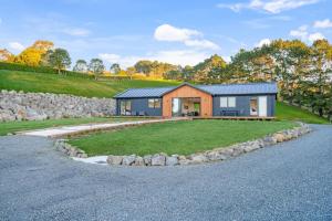 a house on a hill with a gravel driveway at Stunning Modern Hillside Haven near Pukekohe in Bombay