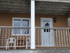 a porch of a house with two chairs and a door at Hunts Point Beachside Suite #13 in Summerville Centre +9 photos