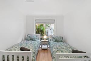 a room with two beds and a window at Shoreline Serenity Waterfront Home in Mannering Park