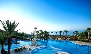 a large swimming pool with palm trees and the ocean at Four Seasons Hotel in Limassol