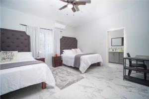 a white bedroom with two beds and a ceiling fan at Spacious Runaway Bay Home Near Beach and Dining in Runaway Bay