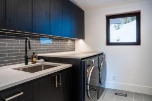 a kitchen with a sink and a washing machine at Sitka Spruce Mountain Chalet in Revelstoke +27 photos