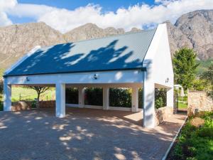 a white building with a blue roof with mountains in the background at Chambray Estate - The Terraces in the Vines in Franschhoek