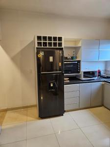 einen schwarzen Kühlschrank in einer Küche mit Mikrowelle in der Unterkunft Hermoso depto en Fdo in Fernando de la Mora