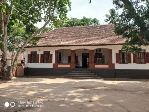 a building in a park with trees in front of it at Alleppey Tharavad in Alleppey