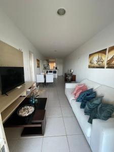 a living room with a white couch and a flat screen tv at Apart Canoa Quebrada vista mar- condominio fechado in Aracati