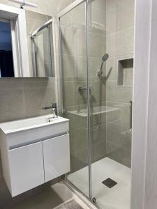 a bathroom with a glass shower and a sink at Gemini Court Apartment in Marsaxlokk +3 photos