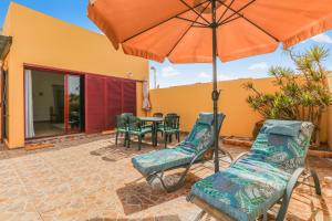 a patio with a table and chairs and an umbrella at Pool Retreat Tamaragua in La Oliva