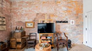 a living room with a tv and a brick wall at Pickle Factory - Cigars and Bourbon Rustic One Bedroom in Covington +17 photos