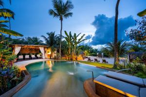 a pool at a resort with palm trees at Hara Pousada e SPA in São Miguel do Gostoso