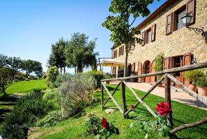 a stone house with a fence and flowers in the yard at Agriturismo Podere l'Aione in Scansano