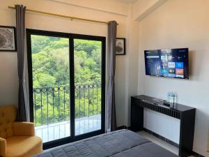 a bedroom with a large window with a view at HOTEL BOUTIQUE ÁRBOL De LA VIDA in Taxco de Alarcón