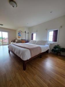 a large bed in a room with wooden floors and windows at Hunts Point Rustic Coastal Retreat with King Bed in Summerville Centre