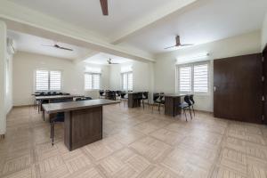 an empty room with tables and chairs and windows at Hotel Mount Kailash Suites in Chennai