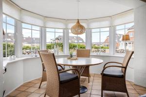 a dining room with a table and chairs and windows at 0476-Romo-Sonder-Frankel-6 in Havneby