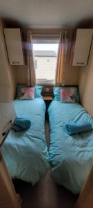two beds in a small room with a window at Willerby Delux - Holiday Home by the Sea - close to the Entertainment Complex-bedding, towels & wifi Included! in Jaywick Sands