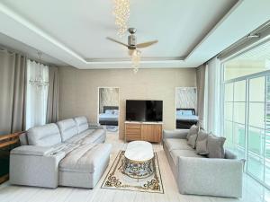 Una sala de estar con un sofá y un televisor. en Kamala Beach Phuket - 4BR Private Luxury Pool Villa, en Kamala Beach