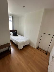 a small bedroom with a bed and a wooden floor at Week and Month Stays 3 Bed Flat and Cinema Room in Rogerstone
