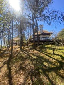 a house in the middle of a field with trees at Hortênsia Boutique - Suites Privativas em Chalés de Luxo in Campos do Jordão