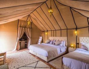 1 dormitorio con 2 camas en una tienda de campaña en Panoramic Desert Camp with jeep pickup included, en Merzouga