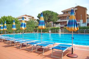 a row of chairs and umbrellas next to a swimming pool at Residence Aurora in Albenga