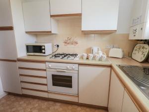 a small kitchen with a stove and a microwave at Flat 9 in Swanage +12 photos