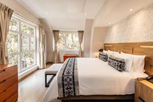 a bedroom with a large bed and windows at Hotel Portón de la Cabrera in Bogotá