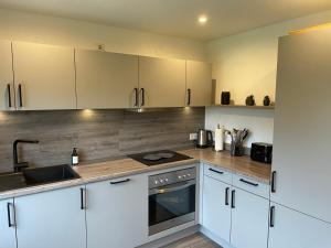 a kitchen with white cabinets and a sink at Moderne Ferienwohnung ab März 2026 mit Saunabereich in Buchet
