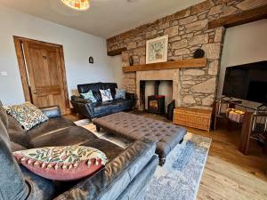 ein Wohnzimmer mit einem Sofa und einem Steinkamin in der Unterkunft Sleepy Cottage in Aviemore