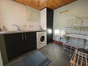 eine Küche mit einer Waschmaschine und einem Waschbecken in der Unterkunft Sleepy Cottage in Aviemore + 8 Fotos