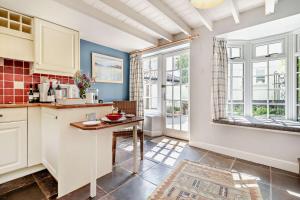 une cuisine avec des armoires blanches et une table dans l'établissement Coach House Cottage Annexe, à Wickham Market