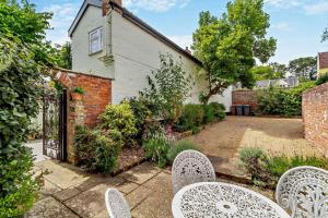 un jardin avec des chaises et un portail vers une maison dans l'établissement Coach House Cottage Annexe, à Wickham Market 21 autres photos