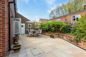 un patio avec une table et des chaises et un bâtiment en briques dans l'établissement Stone Cottage, à Aylsham