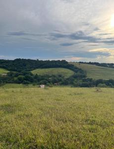a field of grass with the hills in the background at Espaço Encantado STL in São Thomé das Letras +3 photos