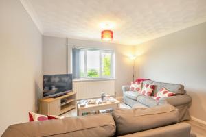 un salon avec un canapé et une télévision dans l'établissement Cornfield Bungalow, à Haddiscoe